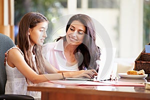 Mother And Teenage Daughter Looking At Laptop Together