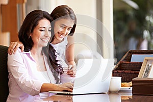 Mother And Teenage Daughter Looking At Laptop Together