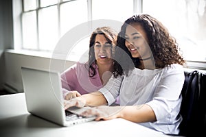 Mother And Teenage Daughter Looking At Laptop Together