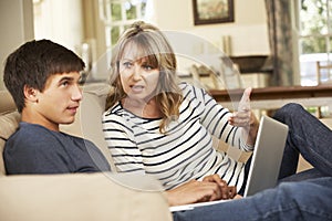 Mother And Teenage Son Arguing On Sofa At Home