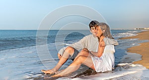 Mother and teenage son hugging and kissing on the beach