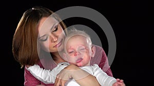 Mother tenderly kissing her cute newborn baby son. Black. Close up