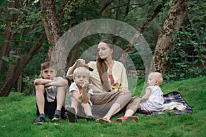 Mother and three children in park in clearing. Family picnic outdoors