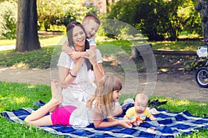 Mother with three children playing in the summer park