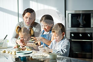 Mother and three children prepare something from the dough.