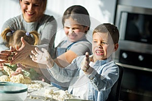 Mother and three children prepare something from the dough.