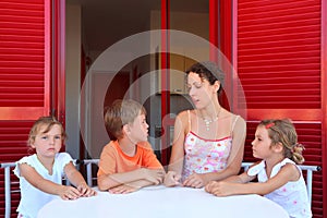 Mother and three children sit on verandah photo