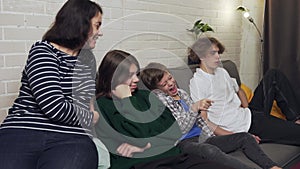 mother and three children, sitting on the sofa, watching TV