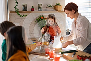 Mother of three little children preparing breakfast in kitchen at home.