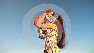 Mother throw her daughter up to blu sky. slow motion filming. Mom plays with small child in her arms against sky. happy