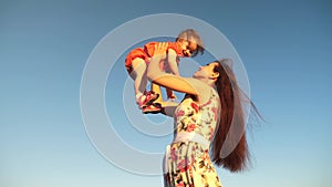 Mother throw her daughter up to blu sky. slow motion filming. Mom plays with small child in her arms against sky. happy