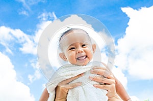 Mother throw up baby daughter with towel on blue sky background