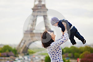 Mother throwing her little son in the air near the Eiffel tower
