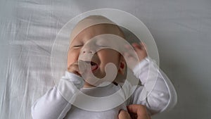 Mother tickles the baby and he laughs lying on the bed