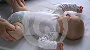 Mother tickles the baby and he laughs lying on the bed