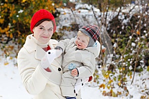 Mother and toddler boy having fun with snow on winter day