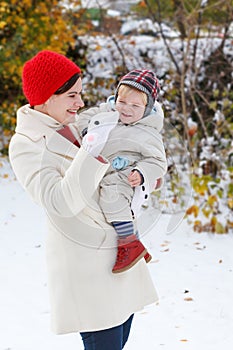 Mother and toddler boy having fun with snow on winter day