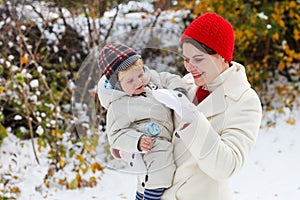 Mother and toddler boy having fun with snow on winter day