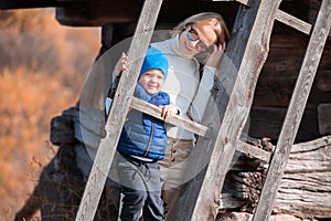 Mother and toddler boy stand near the blade of a large old mill in the Pirogovo Museum in autumn, Kiev, Ukraine.