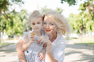 Mother and toddler daughter in the city posing eating ice cream