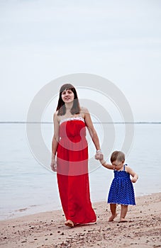 Mother with toddler walking on sand beach