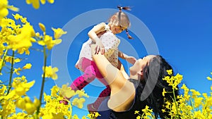 Mother toss up her daughter in yellow field