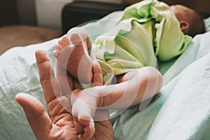 Mother touching cute little newborn baby boy feet.