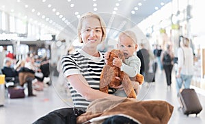 Mother traveling with child, holding his infant baby boy at airport terminal waiting to board a plane. Travel with kids