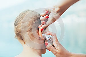 Mother treating little boy ear infection