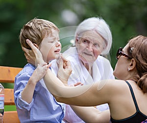 Mother treating scrape on son`s chin photo