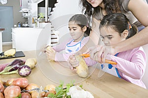 Mother and Twins Peeling Potatoes in Kitchen