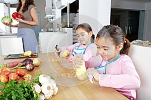 Mother and Twins Peeling Potatoes in Kitchen