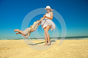 Mother twirling her son on beach