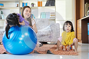 A mother, two Asian daughters, happily playing at home