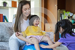 A mother, two Asian daughters, happily playing at home, mother and daughter smiles