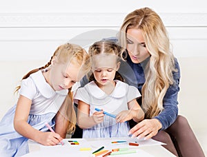 Mother with two beautiful daughters are drawing.
