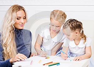 Mother with two beautiful daughters are drawing.