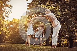 Mother with two child in meadow. Mother holding hands with girl