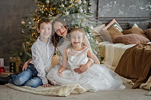 Mother and two childre under Christmas tree