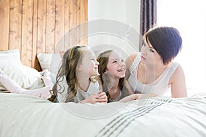 Mother and two children in the bedroom on the bed