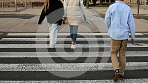 A mother and two children are crossing the street. Road safety. A woman holds a child