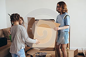 Mother two children at new home with cardboard boxes.