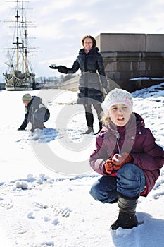 Mother with two children playing a snowball