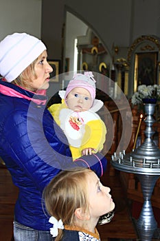 Mother with two children is praying in church. Family prayer. Faith in God