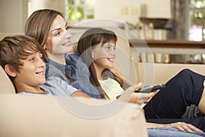 Mother And Two Children Sitting On Sofa At Home Watching TV Together