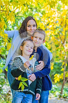 Mother with two children under autumn tree smiling