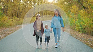 Mother and two children walking in the park and enjoying the beautiful autumn nature. Happy family on autumn walk.