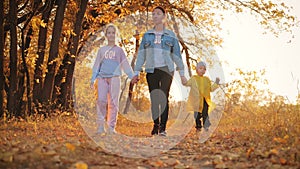 Mother and two children walking in the park and enjoying the beautiful autumn nature. Happy family on autumn walk.