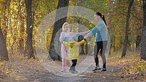 Mother and two children walking in the park and enjoying the beautiful autumn nature. Happy family on autumn walk.