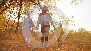 Mother and two children walking in the park and enjoying the beautiful autumn nature. Happy family on autumn walk.